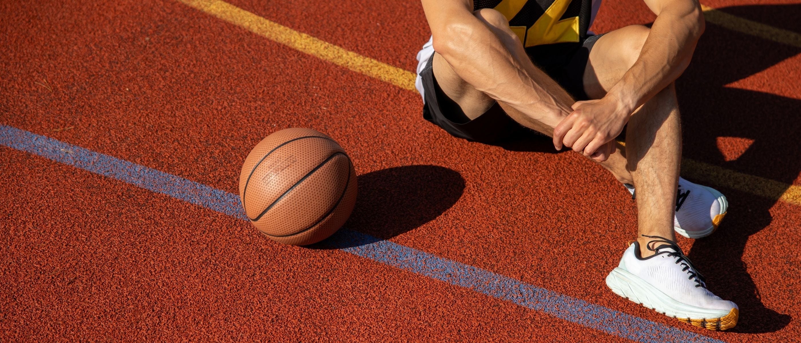 Man on a basketball court with a ball, wearing lifestyle sneakers with replacement laces by Kicks Shoelaces.
